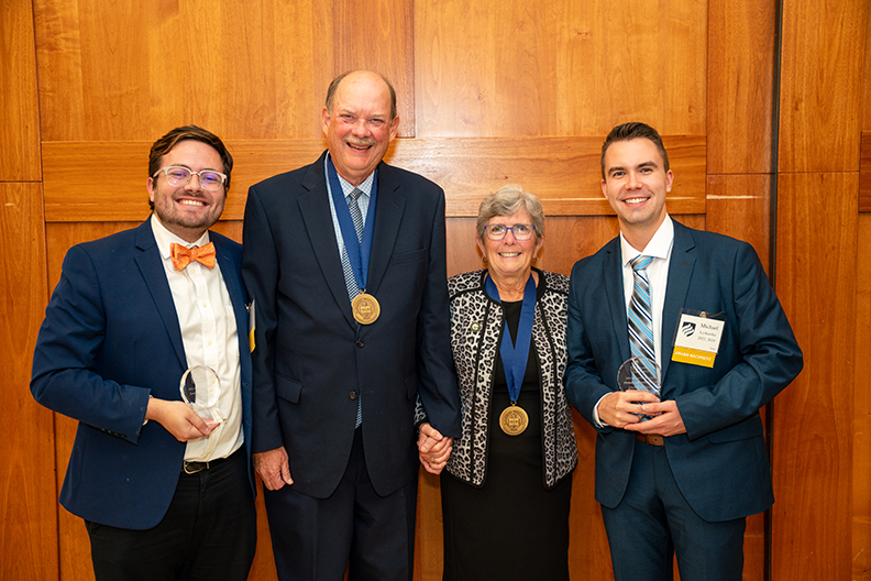 Four people holding awards